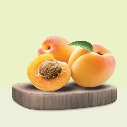 Juicy ripe apricots are displayed on a wooden cutting board against a pastel green background.