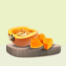 Vibrant orange pumpkin cut into slices and cubes, displayed on a board.