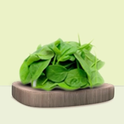 Fresh green spinach leaves are carefully arranged on a wooden board.